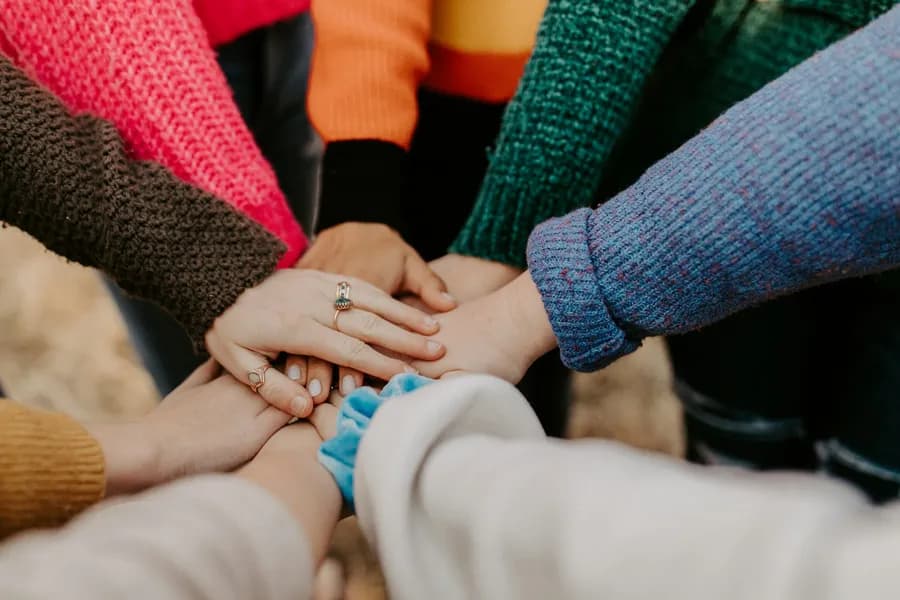 A group of people stacking their hands together in the centre of a circle