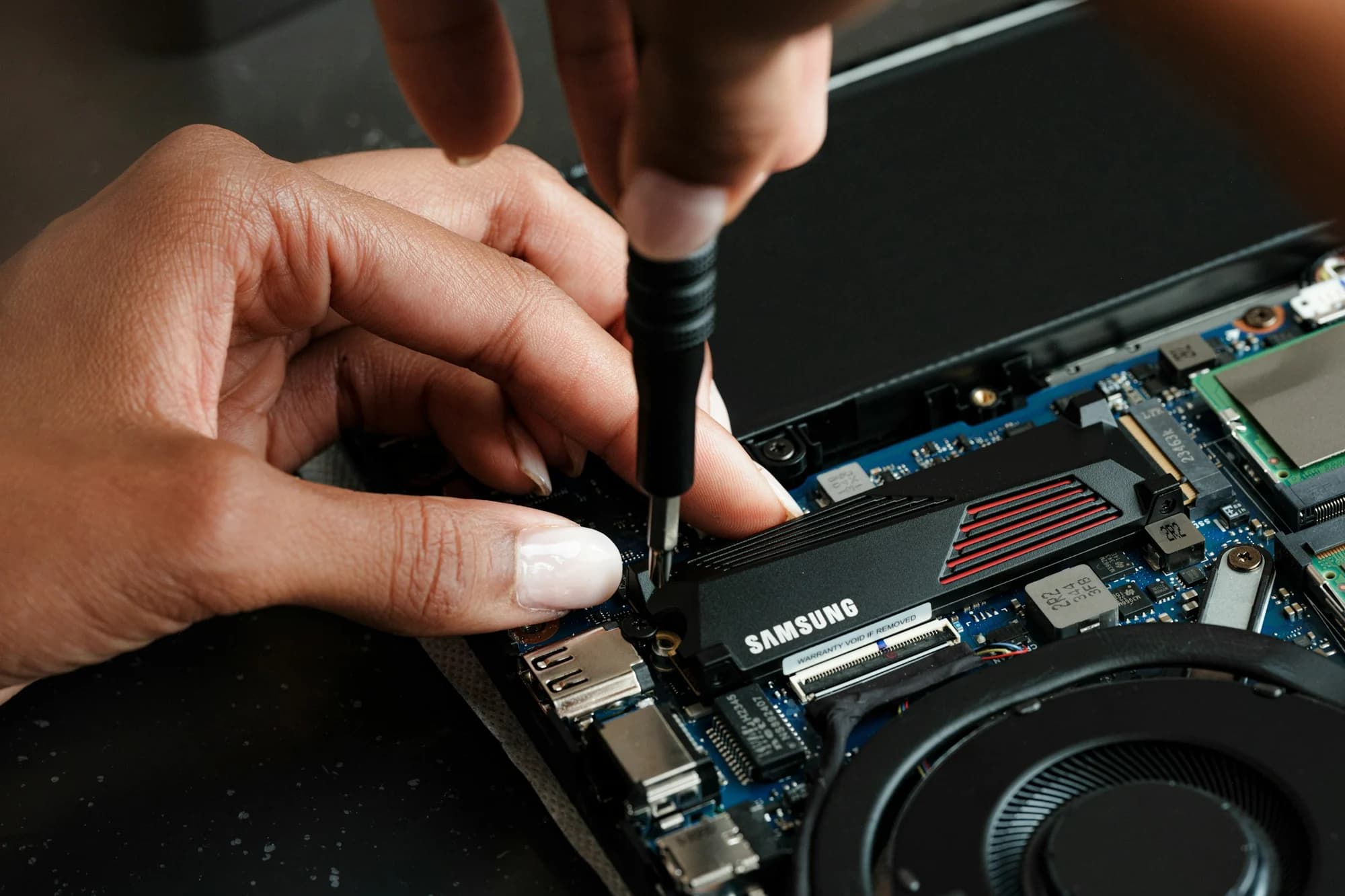 A technician repairing the inside of a laptop with a precision screwdriver